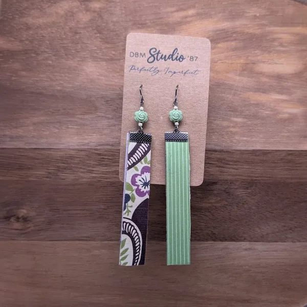 long scrapbook rectangle earrings with florals and swirls of purple, blue, green and brown on the front, green with white vertical stripes on the back. Pewter colored finishes, green and crea